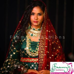 Model in a rich green and red bridal lehenga adorned with intricate embroidery.