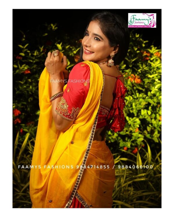 Smiling woman in a vibrant yellow saree with red blouse, showcasing traditional Indian attire.